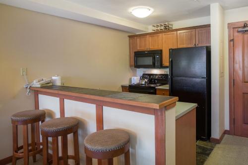 a kitchen with a black refrigerator and bar with stools at 2203 - One Bedroom Den Standard Eagle Springs East condo in Solitude