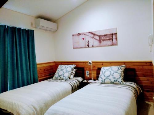 two beds in a room with green curtains at Pension Le Passage - Vacation STAY 11300v in Tottori