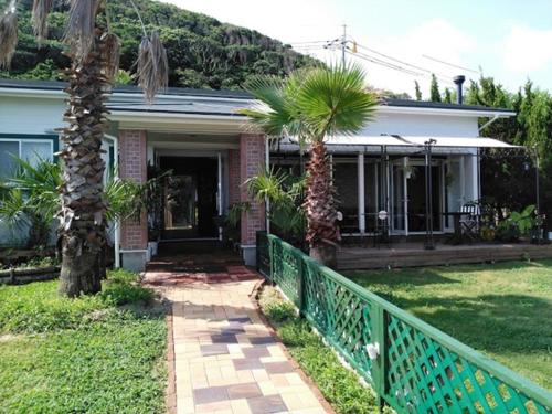 a house with two palm trees and a fence at Pension Le Passage - Vacation STAY 11300v in Tottori