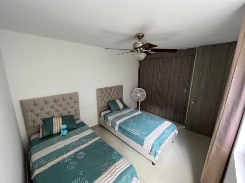 a bedroom with two beds and a ceiling fan at Apartaestudio Carnaval in Barranquilla