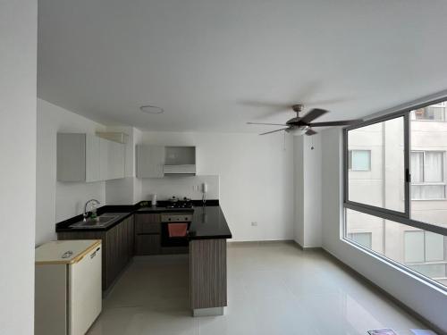 a kitchen with white walls and a ceiling fan at Apartaestudio Carnaval in Barranquilla