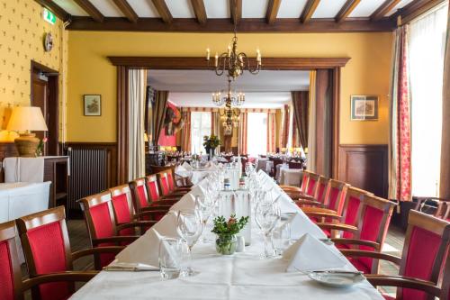 a long table in a restaurant with red chairs at Hotel Cafe Restaurant De Gouden Karper in Hummelo