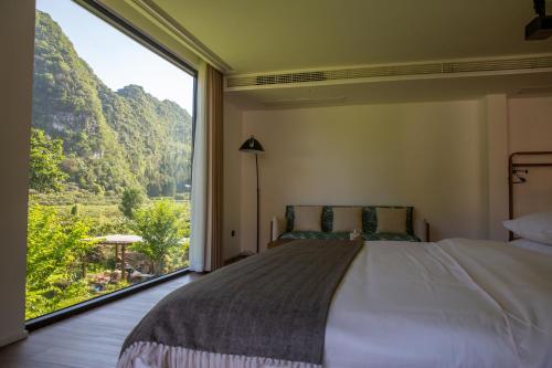 a bedroom with a bed and a large window at Fanzhu Hotel in Xingyi