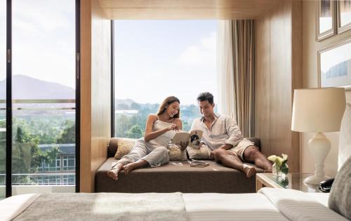 a man and woman sitting on a couch with a dog in a hotel room at Amari Hua Hin in Hua Hin