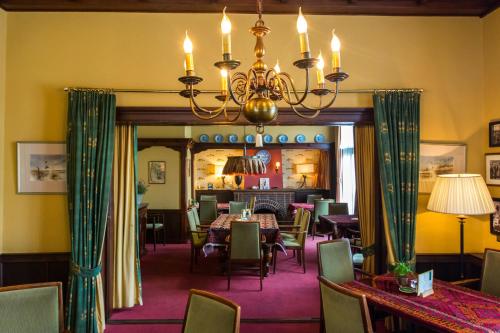 a dining room with tables and chairs and a chandelier at Hotel Cafe Restaurant De Gouden Karper in Hummelo