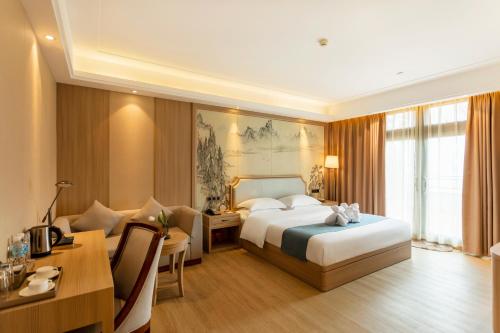 a hotel room with a bed and a table and a desk at Hua Long Hotel Lancang in Lancang