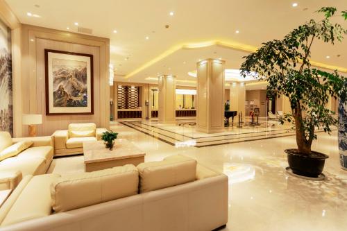 - un salon avec un canapé et un palmier dans l'établissement Hua Long Hotel Lancang, à Lancang