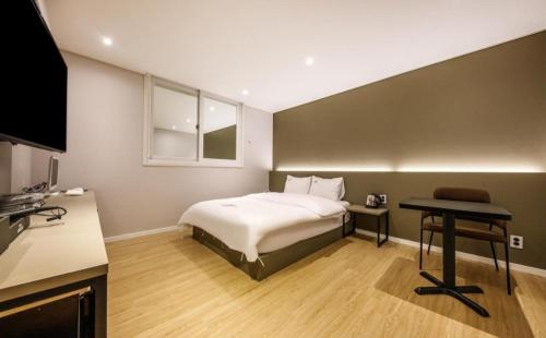 Schlafzimmer mit einem Bett, einem Schreibtisch und einem TV in der Unterkunft Hotel Venesian in Pohang