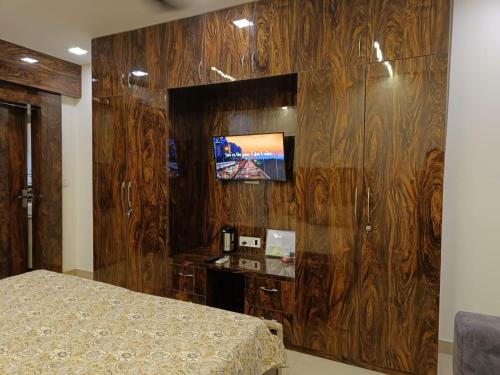 a bedroom with a tv on a wooden wall at Luxury Furnish Studio Apt 623 in DLF Moti Nagar Delhi in New Delhi