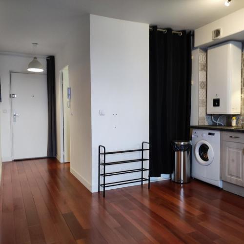 un salon avec un plancher en bois et une laveuse et une sécheuse dans l'établissement Gagny hyper centre, proche RER, Grand studio tout équipé, à Gagny