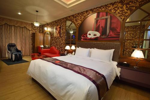a hotel room with a large bed and a red chair at Summer House Motel in Tainan