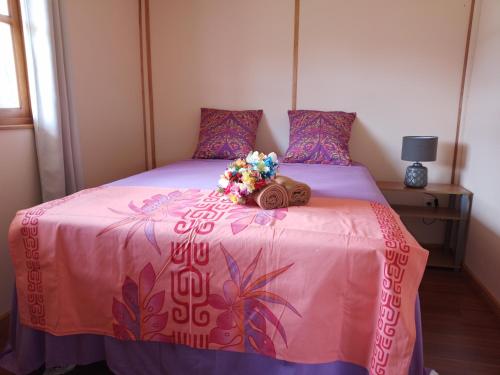 a bedroom with a pink bed with flowers on it at Résidence Tamaumia - Bungalow in Hakamui