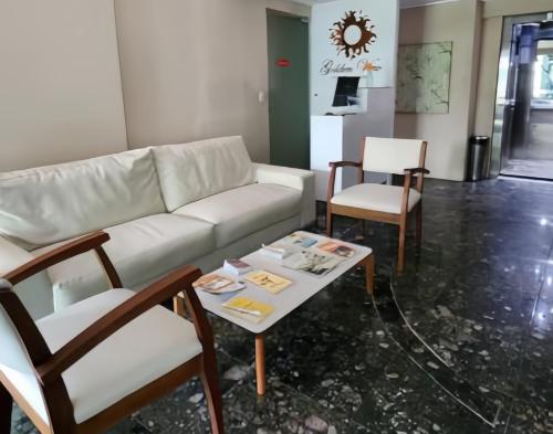 a living room with a white couch and chairs at FLAT Boa Viagem - 50m da Praia - Garagem GRÁTIS - 24H CHECK IN - in Recife