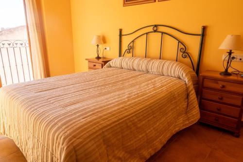 a bedroom with a bed and two night stands and a window at Apartamentos Cuesta de la Cruz in Caravaca de la Cruz