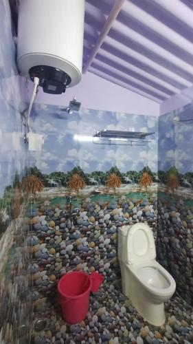 a bathroom with a toilet and a wall with a mural at House of Rabindra Kumar in Deoghar