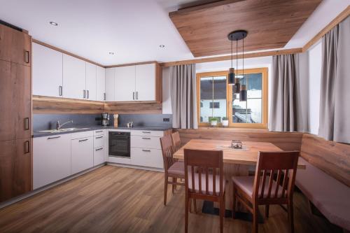 a kitchen with white cabinets and a wooden table at Pension-Appartement Sonnwend in Westendorf