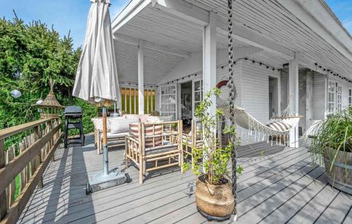 un porche con columpio y sombrilla en Bright And Cozy Summer Cottage On A Secluded Plot, en Kerteminde