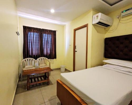 a bedroom with a bed and two chairs and a desk at Hotel Prakash Residency with EV Station in Tiruchchirāppalli
