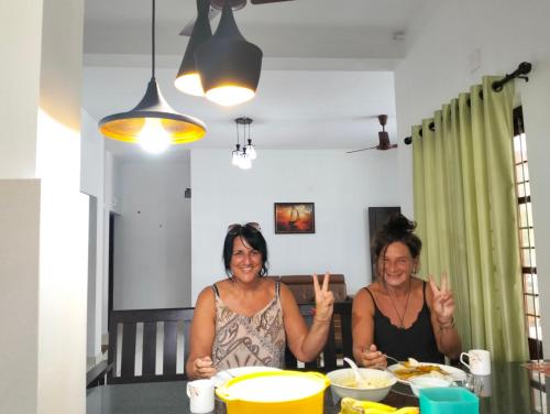 two women sitting at a table with their hands up at Bachan's Casa in Cherai Beach