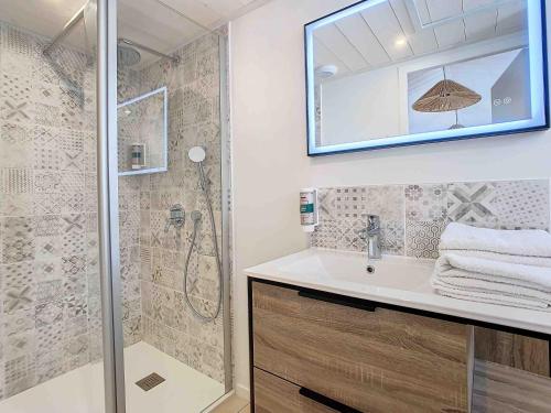 a bathroom with a shower and a sink and a mirror at La Tranquillité in LʼHerbaudière