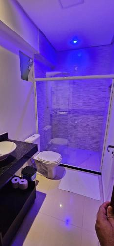 a bathroom with a toilet and a shower with purple lights at Residencial Oliveira - Charmoso e Aconchegante in Itacaré