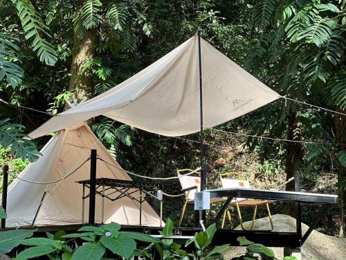 a tent with a table and a chair in a forest at The camp Maekampong in Ban Pok Nai