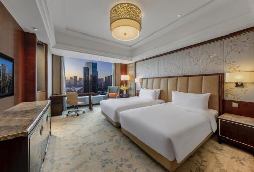 a hotel room with two beds and a desk at Shangri-La Shenyang in Shenyang