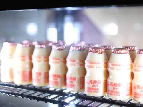 a row of milk bottles on a conveyor belt at Fukeikan 風景館 in Takayama