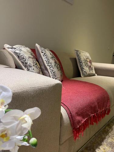 eine Couch mit einer roten Decke und Kissen darauf in der Unterkunft Thorntree Self Catering Apartment, Witbank in Witbank