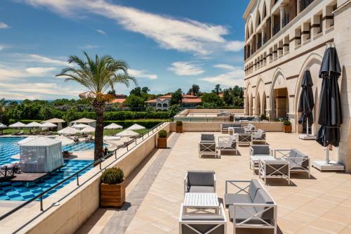 a hotel patio with chairs and a swimming pool at Kempinski Hotel The Dome Belek in Belek