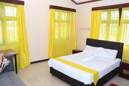 Schlafzimmer mit einem großen Bett und gelben Vorhängen in der Unterkunft Swahili House Mweru villa in Mombasa