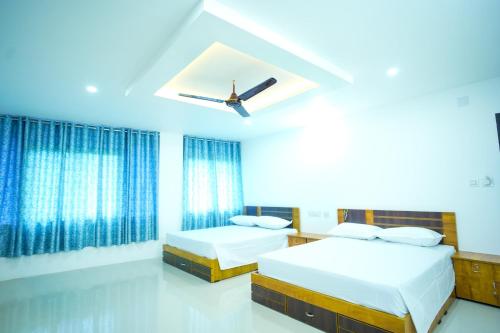 a bedroom with two beds and a ceiling fan at PIOUS B RESIDENCY in Mundakāyam