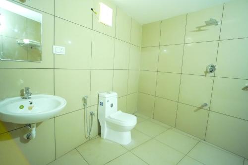 a white bathroom with a toilet and a sink at PIOUS B RESIDENCY in Mundakāyam