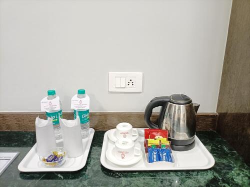 two white trays with a tea kettle on a counter at Hotel Zain Grande in Chennai