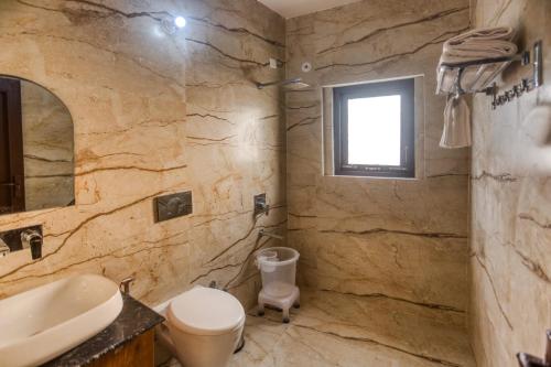 a stone bathroom with a toilet and a sink at Pitaara Cottage in Kota Bāgh