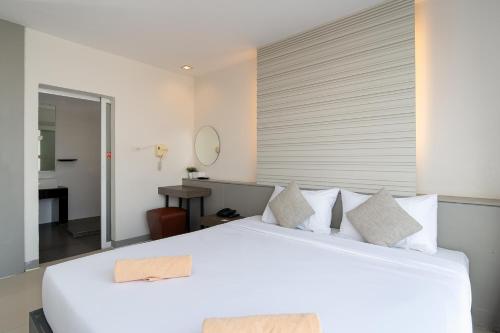 a bedroom with a large white bed and a bathroom at Leenova Hotel in Bangkok