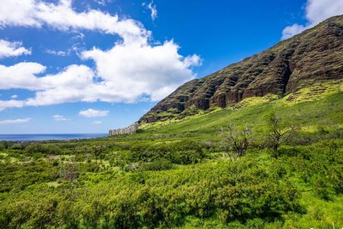 a green hill with the ocean in the background at @Marbella Lane-Pōmaika'i LoveNest Ocean+MT View in Waianae