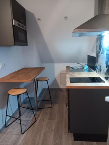 - une cuisine avec une cuisinière et deux tabourets de bar dans l'établissement Studio Est proche centre ville, à Loudéac