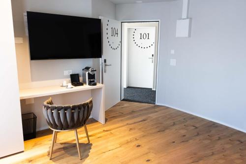 Zimmer mit einem Schreibtisch, einem TV und einem Stuhl in der Unterkunft Hotel Rondo - Self-Check-in in Wil