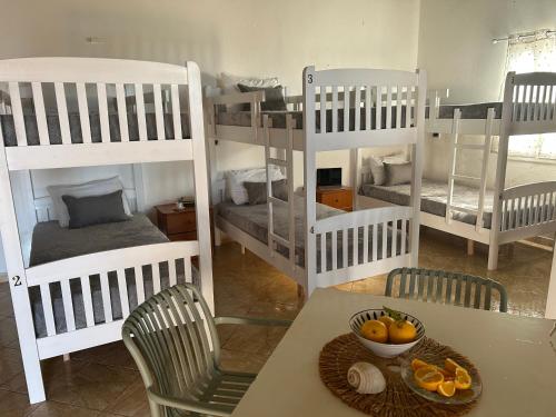 a room with four bunk beds and a table with a bowl of fruit at Hostel on the Hill - by Filikuri Beach in Himare