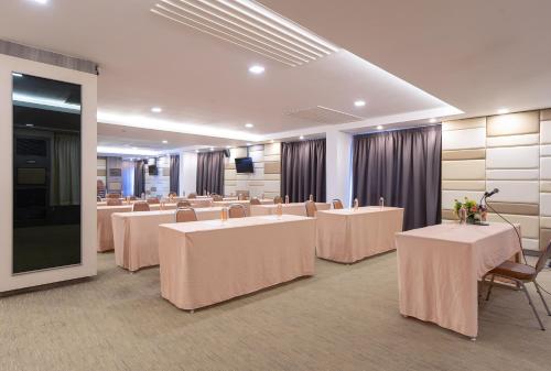 a conference room with tables and chairs and a screen at Leenova Hotel in Bangkok