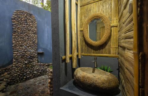 a bathroom with a stone sink and a mirror at Fab - Bamboo Hut with Open Shower in Munnar