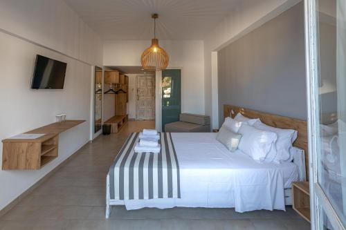 a bedroom with a large white bed and a desk at Triton Authentic Cretan Hotel in Tsoútsouros