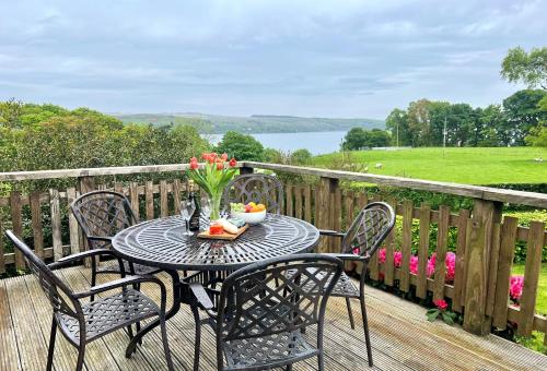 einen Tisch mit einer Blumenvase auf dem Deck in der Unterkunft Alder Cottage in Blairmore
