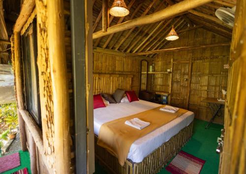 a bedroom with a bed in a wooden house at Fab - Bamboo Hut with Open Shower in Munnar
