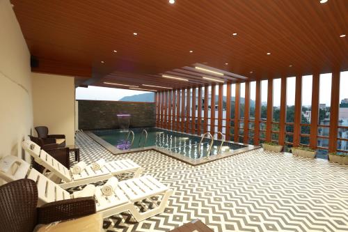 a large room with a pool and a balcony with chairs at Hotel Taviral Regency in Udaipur