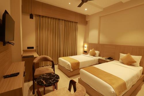 ein Hotelzimmer mit 2 Betten und einem Stuhl in der Unterkunft Hotel Taviral Regency in Udaipur
