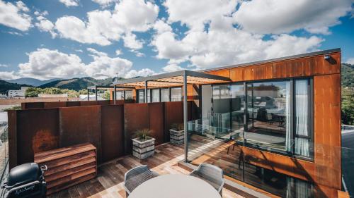 a house with glass walls and a deck with chairs at Beautiful urban apartment 1 in Nelson