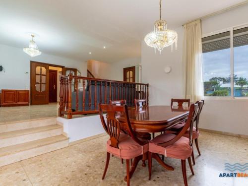 a dining room with a table and chairs and a chandelier at APARTBEACH EL PINAR CON PISCINA y BARBACOA in Reus