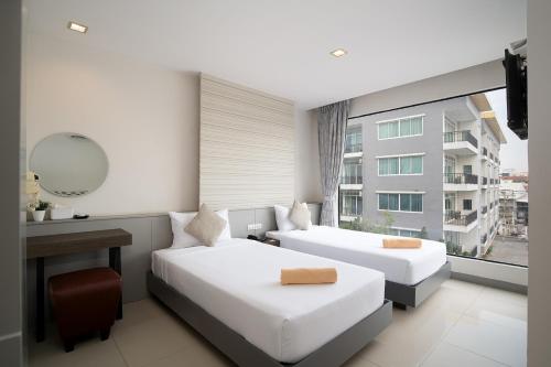 a bedroom with two beds and a desk and a window at Leenova Hotel in Bangkok